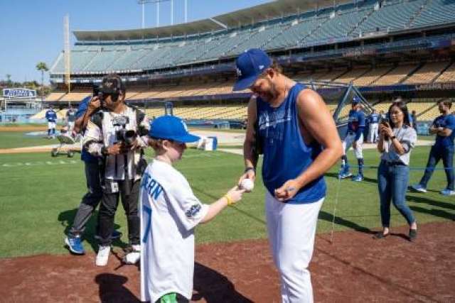 Kellen Kershaw hands a baseball to a young Kellen McGovern on a baseball field.