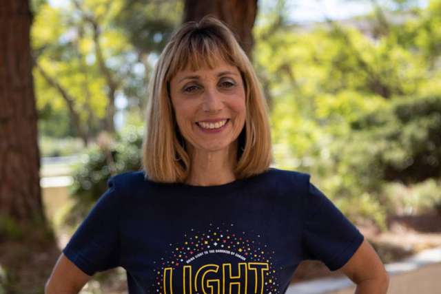 Judy Reiter smiling outdoors in a navy "Light the Night" T-shirt