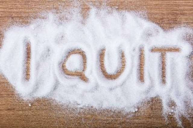 The phrase "I QUIT" written in granulated sugar on a wooden surface.