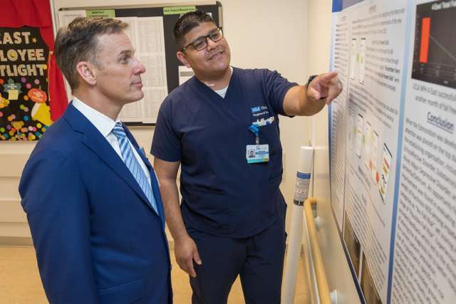 Clinical Nurse Abraham Urias, right, presents his fall prevention project poster to Chief Nursing Officer Patrick Loney in the 4 East Adult Psychiatric unit.