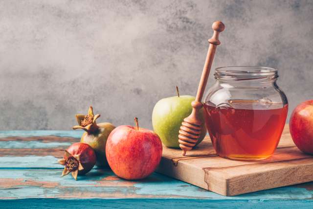 A glass jar filled with honey sitting on a cutting board