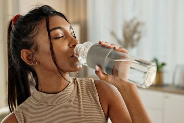 Woman drinking water from a reusable bottle