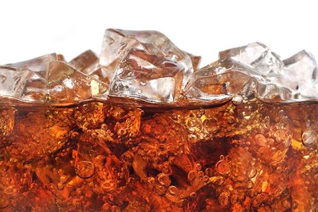 Close-up of a glass filled with cola and ice cubes, showing bubbles and condensation for a refreshing look.