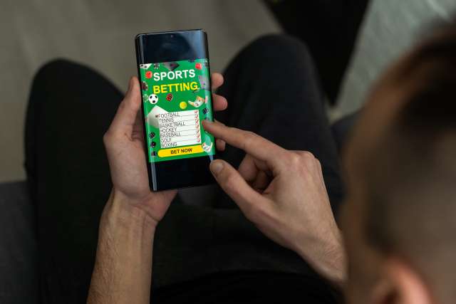 A man looks at a sports betting website on his smartphone.