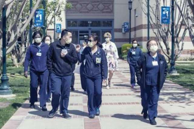 Group of UCLA nurses wearing masks while walking together down a pathway outside