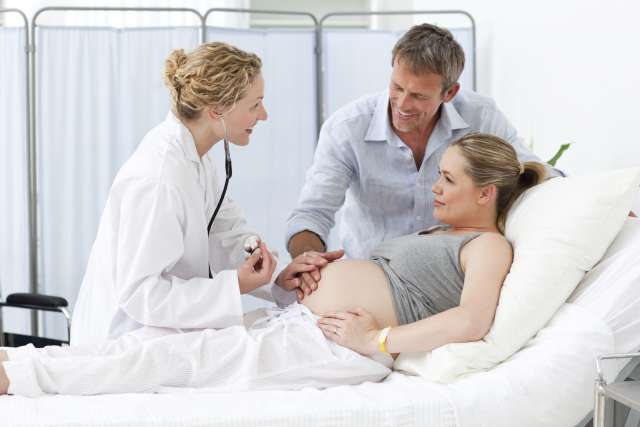 Pregnant woman with father in hospital talking to a doctor