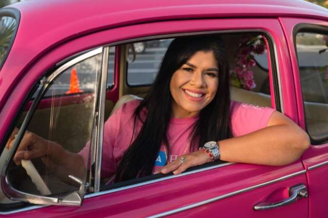 Corina Guzman sitting in a pink VW Beetle