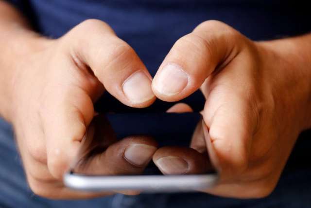 Close-up of hands holding a smartphone and typing on the screen