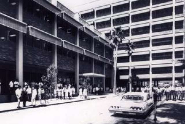 UCLA School of Dentistry exterior with a crowd and parked car, in black and white.