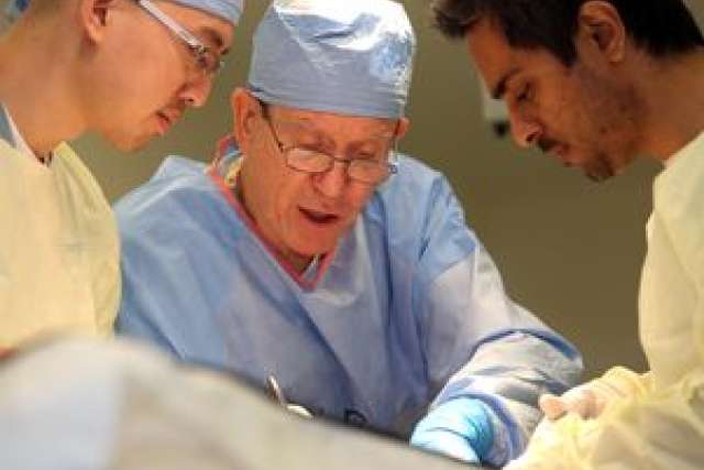 Surgeons in scrubs performing a medical procedure in an operating room.