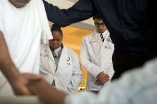 Medical professionals comforting a patient during chaplain rounds.