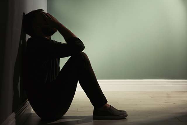 Depressed man leaning against wall
