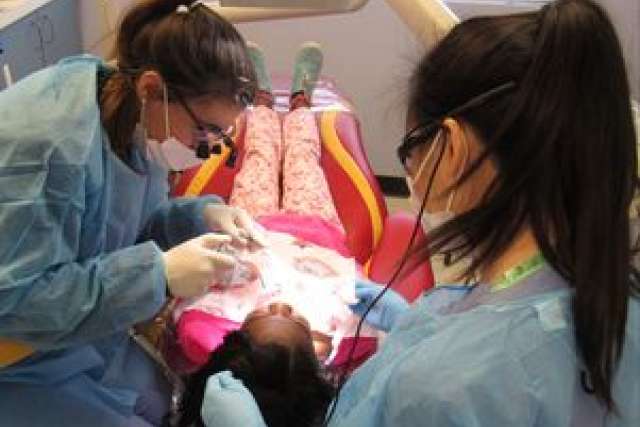 Child at dentist UCLA Dentistry being treated by two masked dental staff