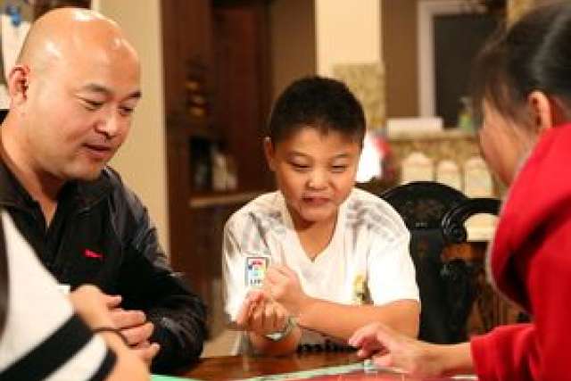 A family playing a board game at a table in a cozy setting.