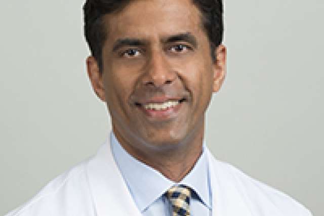 Portrait of Christopher Saigal in a white lab coat and patterned tie.