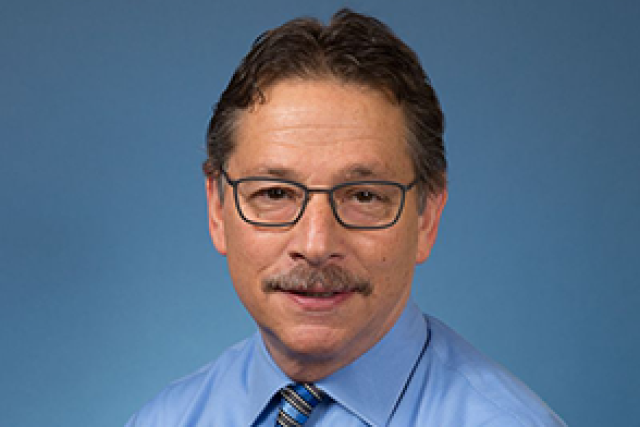 Dr. Donald Kohn headshot wearing glasses, a light blue button up shirt, and a stripes tie.