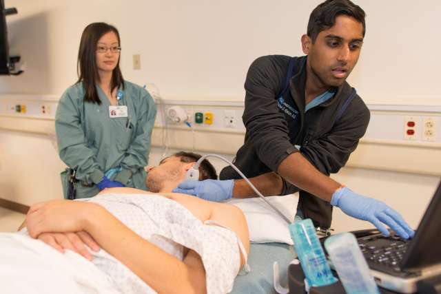 A medical student performs an ultrasound under faculty supervision.