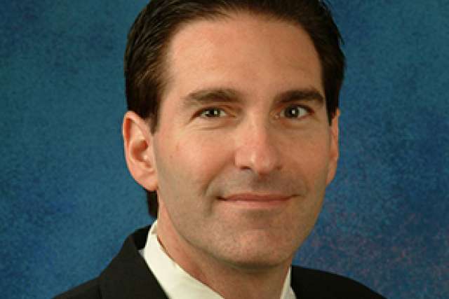 Dr. Gregg Fonarow in suit and tie on blue backdrop.
