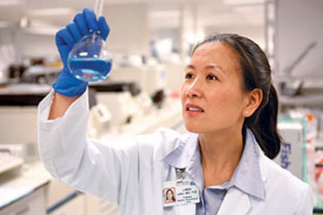 Dr. Linda Liau looking at a test tube.