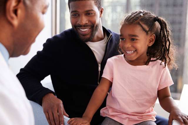 Father And Daughter Having Consultation With Pediatrician In Hospital Office