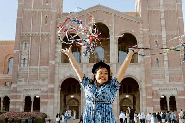 Gabriela Lopez celebrating with colorful streamers in front of Royce Hall.