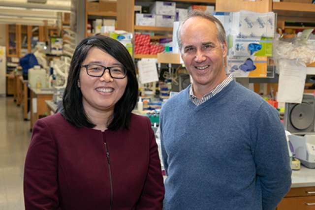 Two researchers pose together in a laboratory setting.
