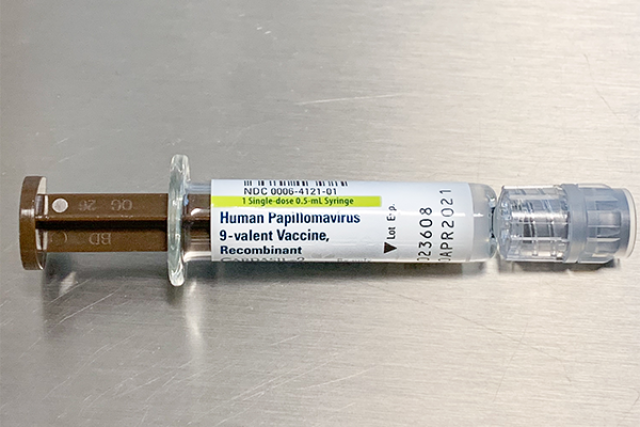Syringe with HPV vaccine placed on a silver tray