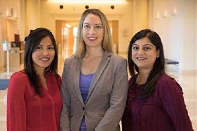 Three women pose together in a well-lit indoor setting.