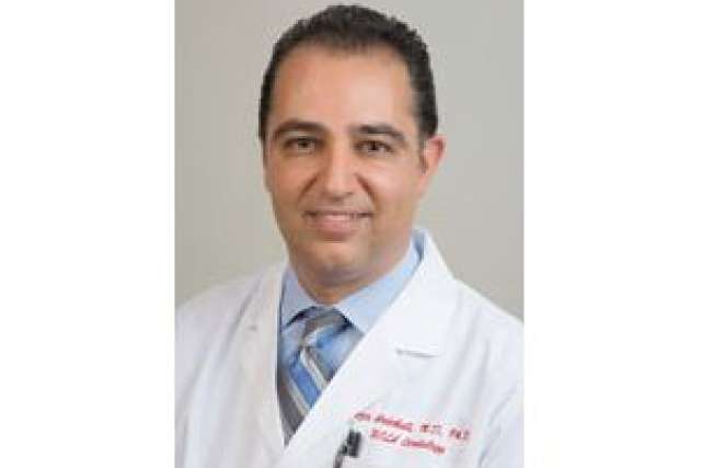Male medical professional wearing a white coat and blue tie.