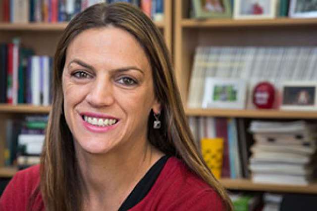 Portrait of Lara Ray in a library setting, wearing a red top and earrings.