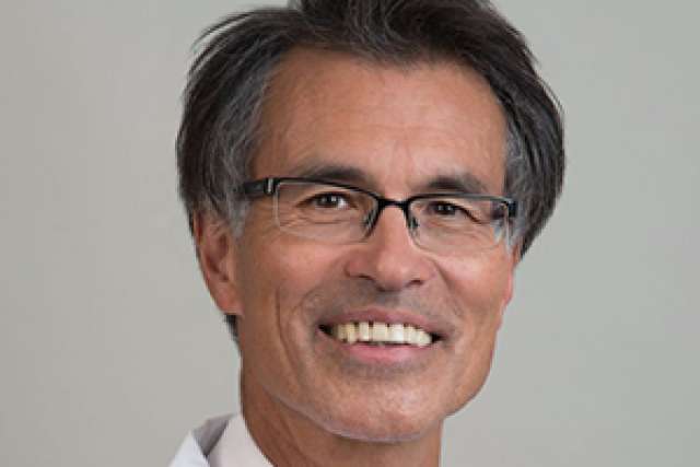 Mario Deng headshot in white coat and pink tie