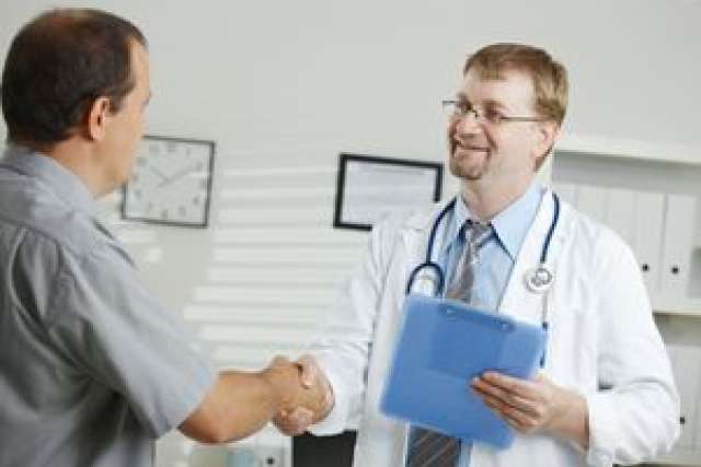 A doctor and a patient shaking hands in a medical office.
