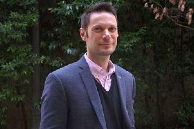 Dr. Patrick Allard in blazer and sweater with leafy background
