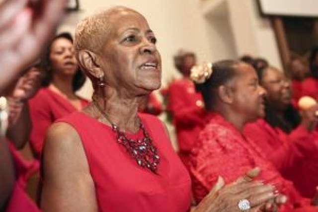 Audience members in red attire clapping during an event.