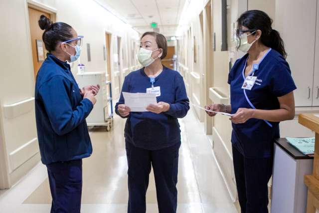 UCLA Health nurses speaking at work in a hallway.