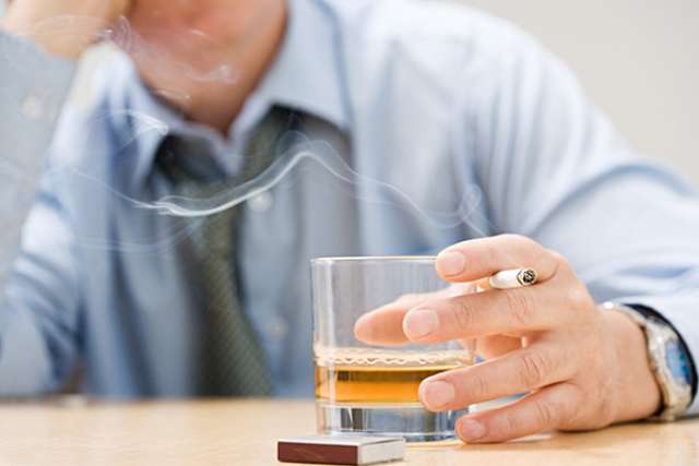Man at table with cigarette and drink