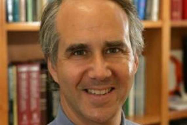 Daniel Geschwind wearing blue shirt with tie standing in front of book shelf