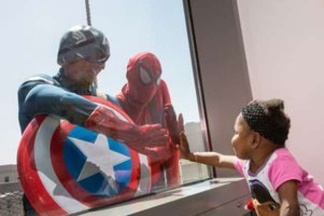 Captain America and Spiderman greeting patient Erin outside window on 5th floor