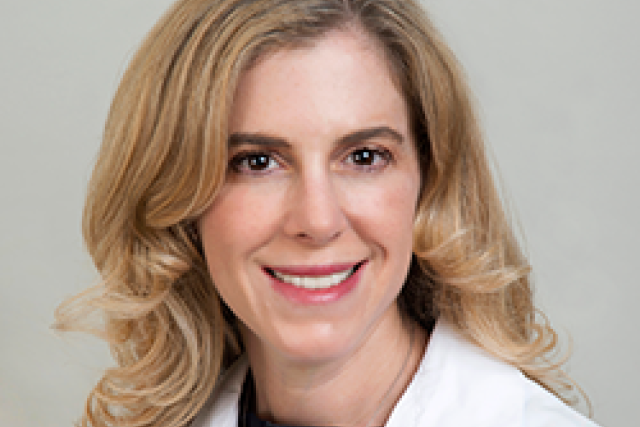 Dr. Tamara Horwich smiling and wearing a black shirt with her lab coat on top.