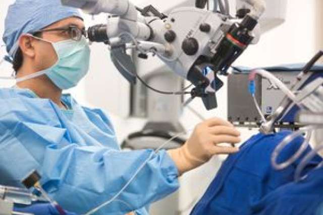 Surgeon operating a robotic surgical system in a medical setting.