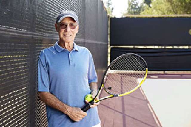 Tom Stutz stands with a tennis racket on a court.