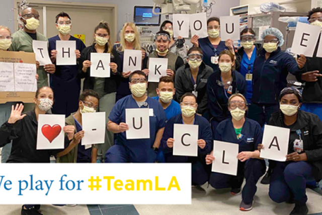 UCLA Health care team holding thank-you signs in masks and scrubs, showing support for #TeamLA during the COVID-19 pandemic.