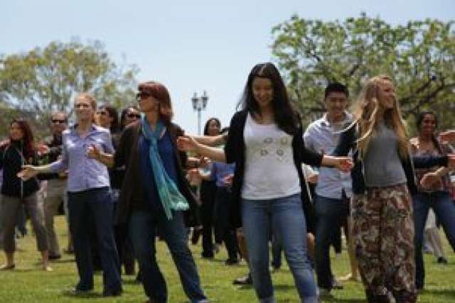 A group of people dancing outdoors on a sunny day at UCLA.