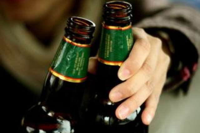 Two beer bottles with a hand reaching toward them.