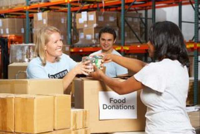 Volunteers sorting food donations in a warehouse setting.