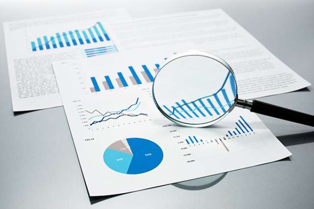 Sheets with charts and graphs and a magnifying glass
