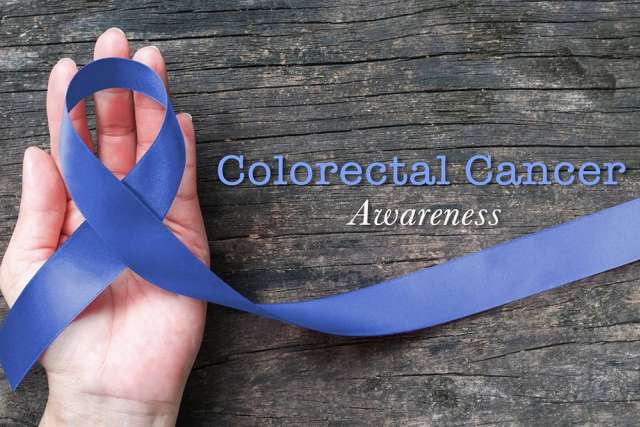 Hands holding blue colorectal cancer awareness ribbon on wood