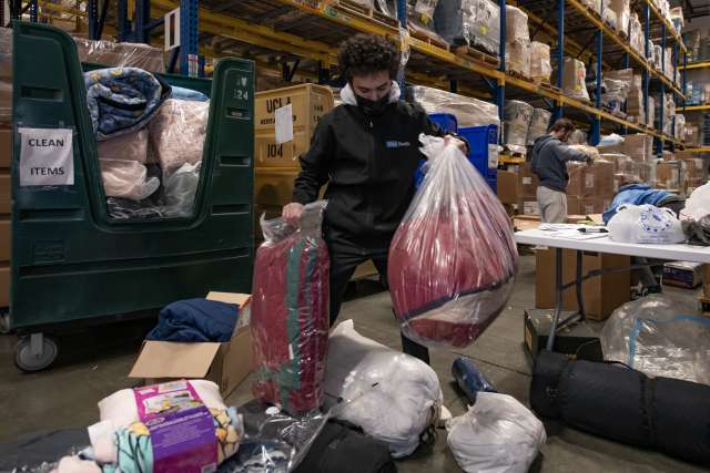 A man holding plastic bags of donations in a warehouse