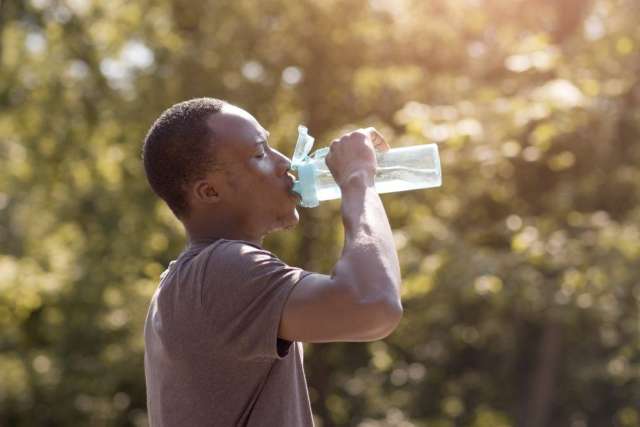 Man drinking from water bottle outdoors