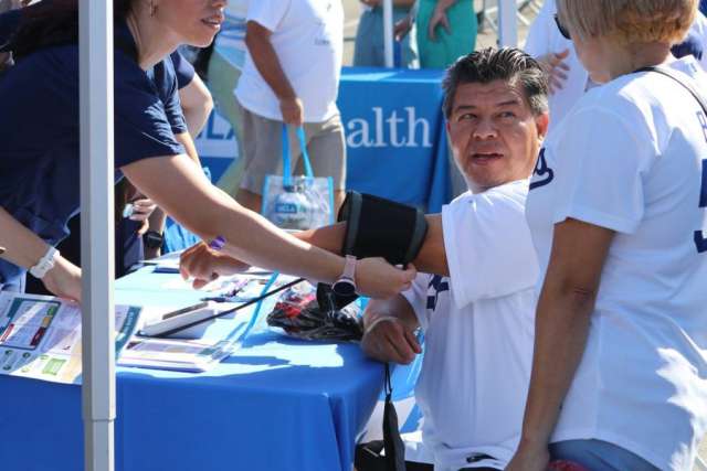 Village booth staff assists seated attendee while another person watches